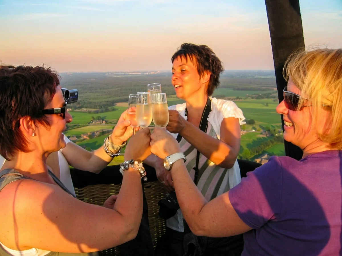 Drie passagiers proosten met champagne in de mand boven Brabant